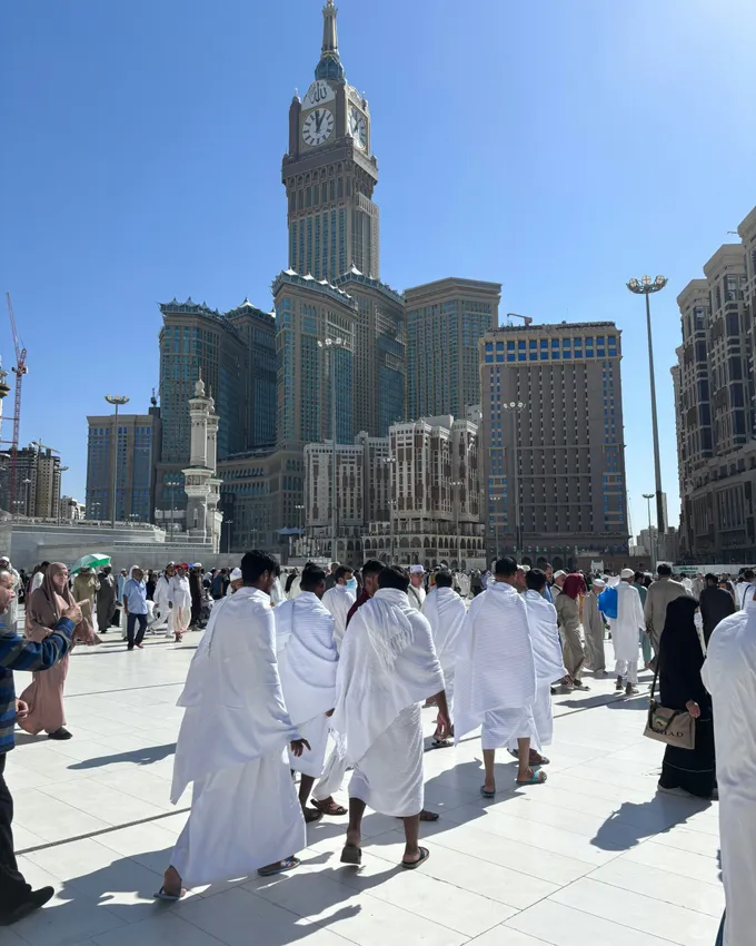 Jamaah berihram berjalan menuju Masjidil Haram dengan latar menara jam Abraj Al Bait, Makkah
